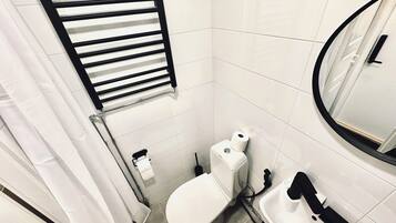 A bathroom with a toilet, a sink, a towel rack, and a mirror.