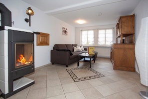 A living room with a fireplace, a sofa, a coffee table, and a wooden cabinet. - Apartment 'Katze' with Shared Terrace, Shared Garden and Wi-Fi (Schmallenberg)