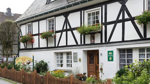 A traditional half-timbered building with a wooden door, multiple windows, and flower boxes. - Apartment 'Hase' with Mountain View, Shared Terrace and Wi-Fi (Schmallenberg)