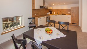 A modern kitchen with white cabinets, a wooden countertop, and a dining area with a table set for two. - Apartment 'Kuhstall' with Shared Terrace, Shared Garden and Wi-Fi (Schmallenberg)