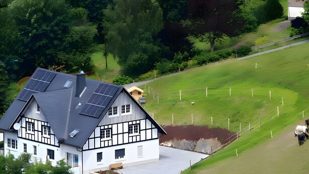 A large house with a steep roof, solar panels, and a well-maintained lawn.