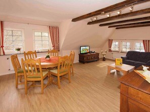 A living room with a wooden dining table, chairs, a sofa, a television, and a fireplace. - Apartment 'Ziege' with Mountain View, Shared Terrace and Wi-Fi (Schmallenberg)