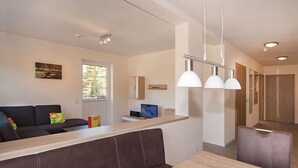 Un salon moderne avec un canapé, une table à manger et un coin cuisine à l’arrière-plan.