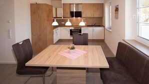 Une cuisine moderne avec des meubles en bois, un four à micro-ondes encastré et des luminaires suspendus.