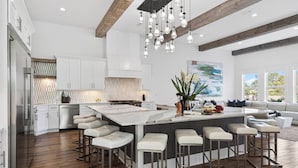 A modern kitchen with white cabinetry, a large island with bar stools, and a hanging light fixture. - Sleeps 39 | 2 Luxe Homes w/ Free Golf Cart, Private Pool+Spa | 3 Blocks to Beach (Santa Rosa Beach)