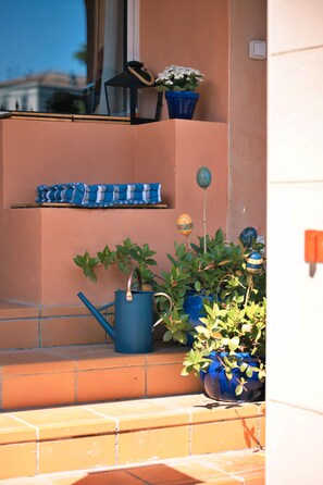 A balcony with potted plants, a blue watering can, and a blue chair. - Le 1693 – Luxury apartment with 2 suites, jacuzzi and river-view terrace (Limoux)