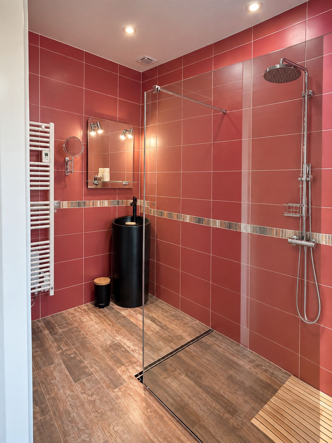 A modern bathroom with a glass-enclosed shower, a vanity with a mirror, and a heated towel rail.