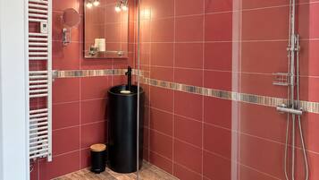 A modern bathroom with a glass-enclosed shower, a vanity with a mirror, and a heated towel rail.
