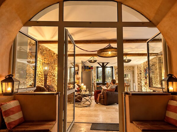 A cozy interior with a stone wall, a dining area, and a seating area with cushions.