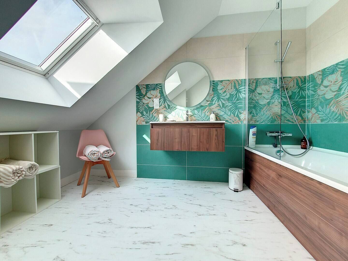 A modern bathroom with a skylight, a wooden vanity, a marble floor, and a green leaf-patterned wall.