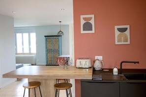 A kitchen with a wooden island, bar stools, a toaster, a kettle, and a sink.