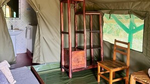 A tented room with a bed, a wooden chair, a small table, and a window with a view. - Bwana Tembo Safari Camp (Pakwach)