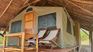 A rustic tent with a wooden door, two lounge chairs, and a wooden table on a raised platform. - Bwana Tembo Safari Camp (Pakwach)
