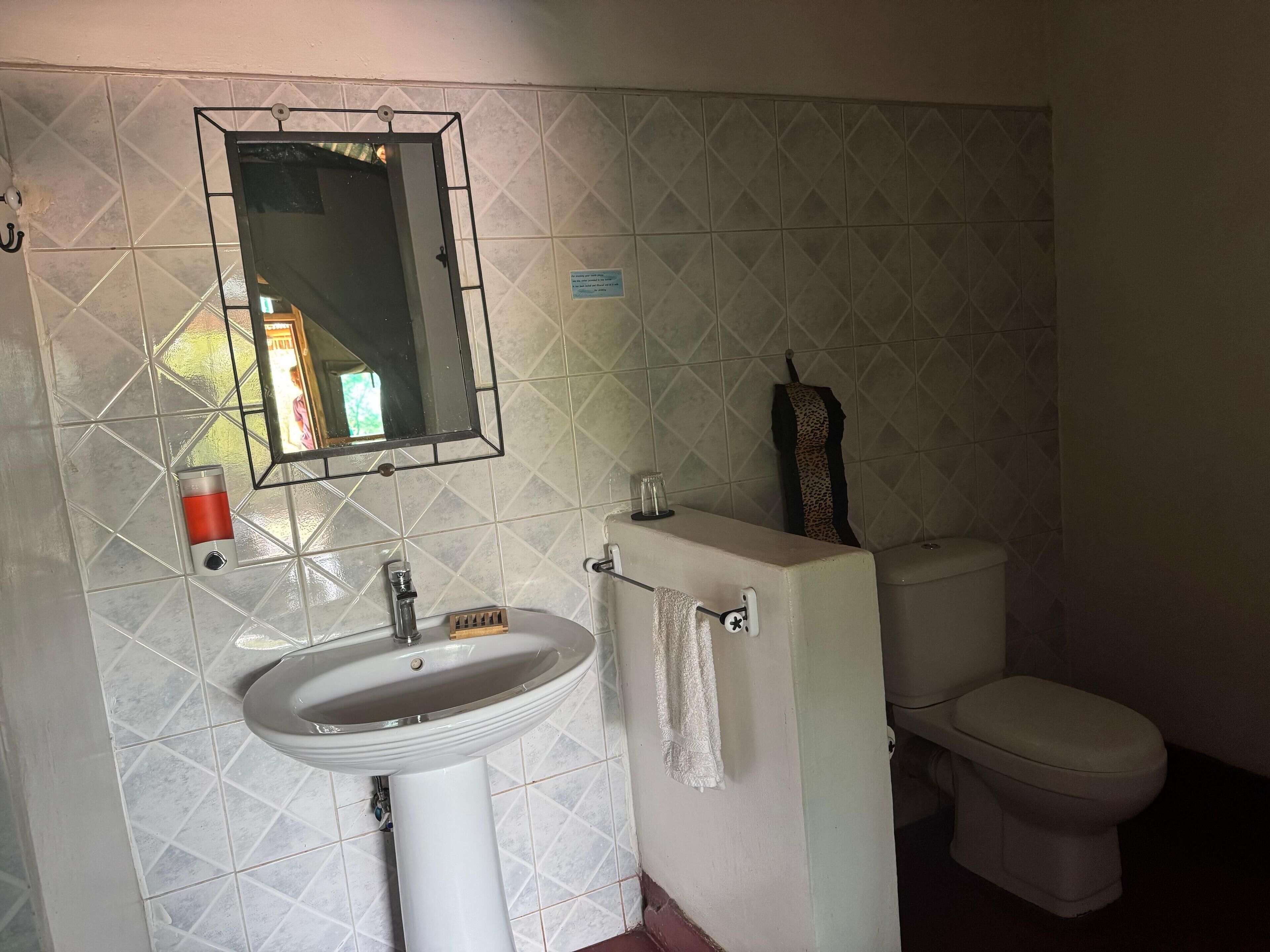 A bathroom with a white sink, a mirror, a toilet, and a towel hanging on the wall.
