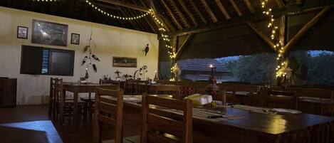 A dining area with wooden tables and chairs, string lights, and wall art.