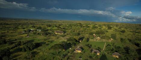 A rural landscape with scattered houses surrounded by greenery and a cloudy sky.