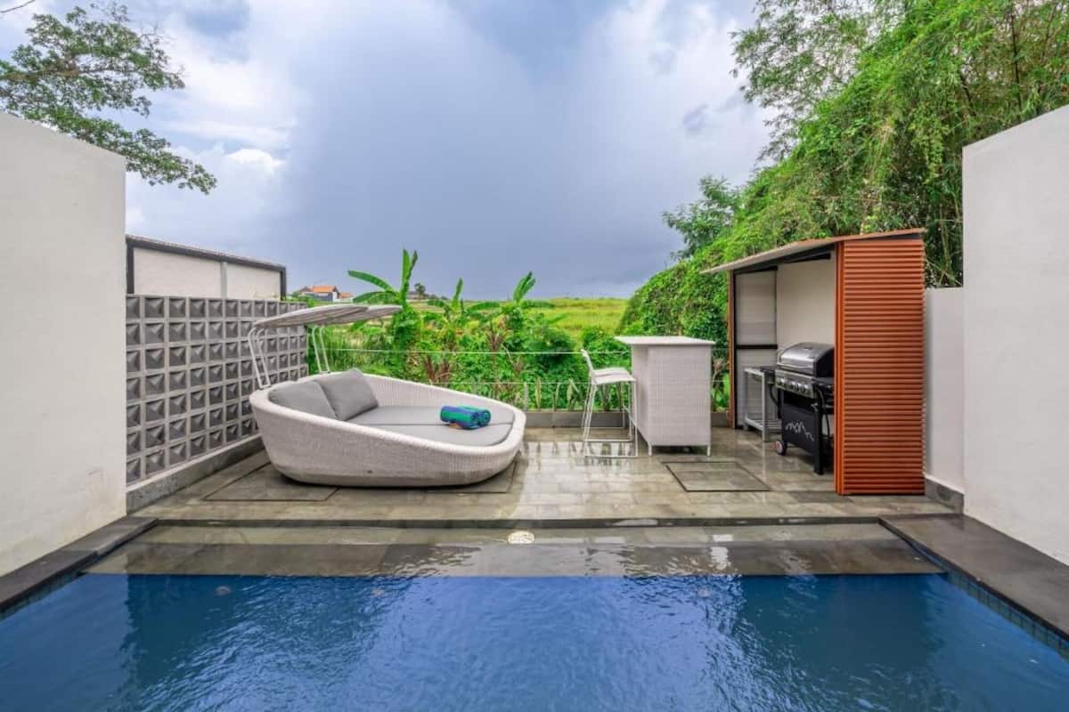 A swimming pool with a white lounge chair and a grill area.