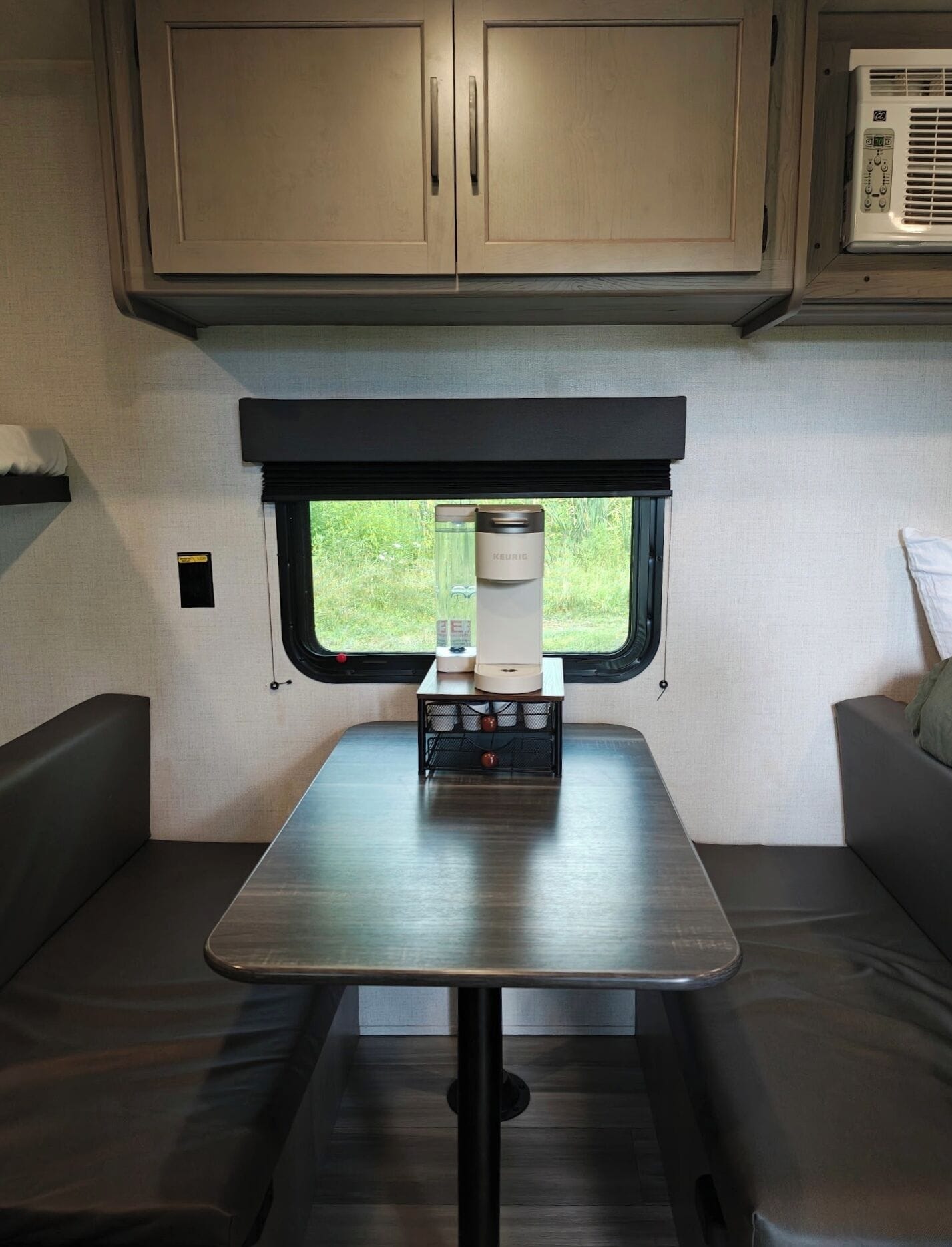 A compact RV interior with a kitchenette, a table, and a window.