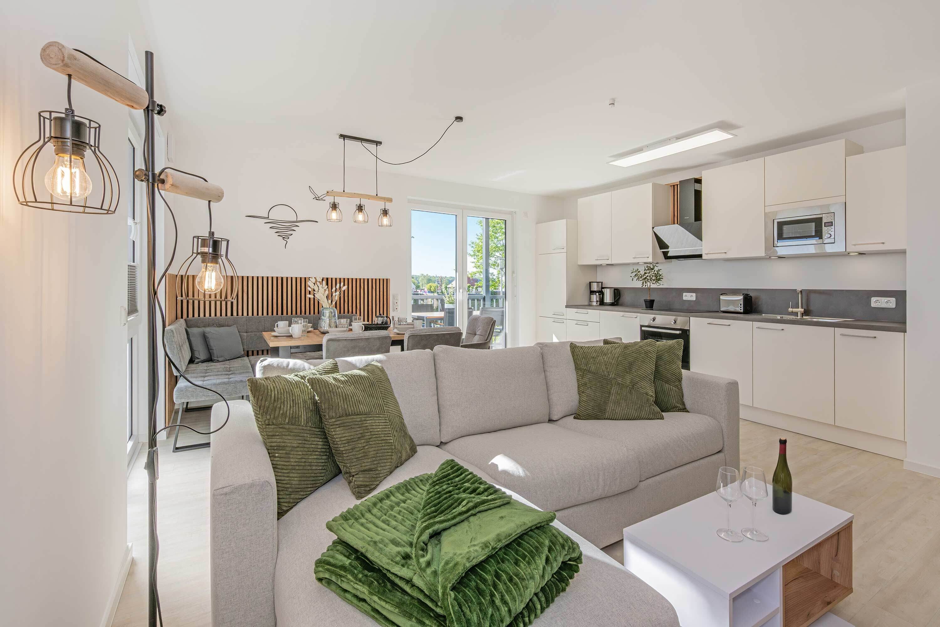 A modern living room with a sofa, a coffee table, and a kitchen area with white cabinets and a microwave.