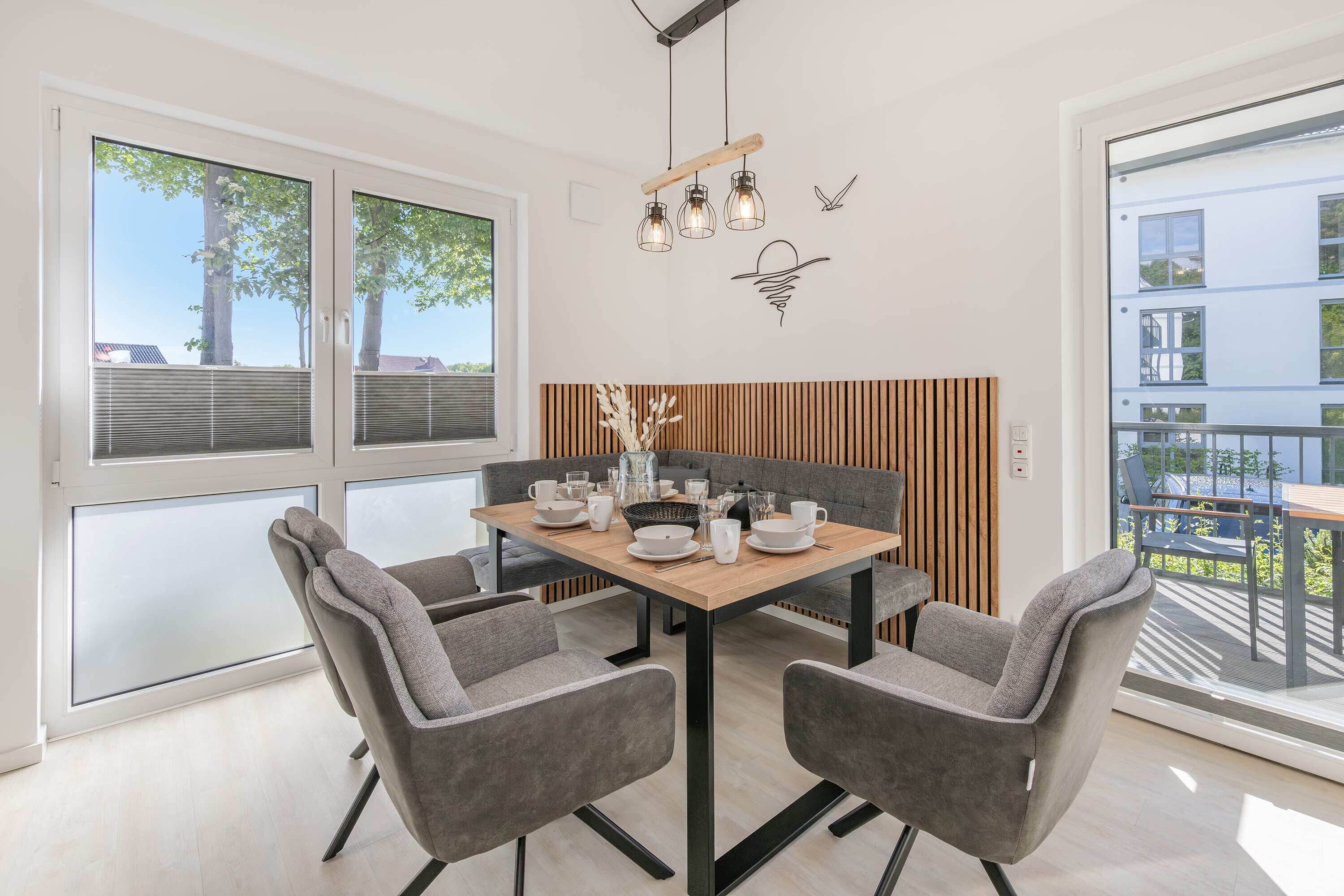 Uma sala de jantar moderna com mesa de madeira, cadeiras estofadas cinzas e um banco.