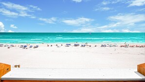 Une plage de sable blanc, avec une eau turquoise et limpide, et quelques parasols.