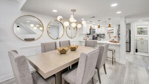 Une cuisine moderne avec des meubles blancs, un îlot central et des luminaires suspendus.