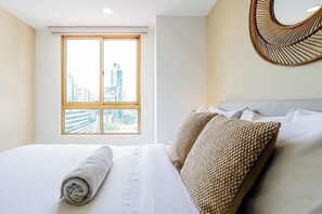 Een hotelkamer met een bed, een raam met uitzicht op de stad en een wanddecoratie van geweven materiaal.