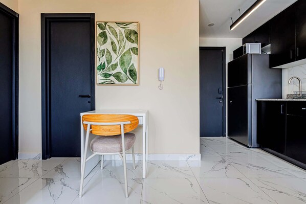 A modern kitchen with black cabinets, a marble countertop, and a built-in oven.