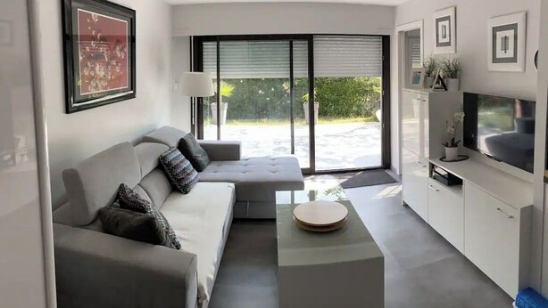 A modern living room with a grey sofa, a coffee table, and a TV on a white cabinet. - APPARTEMENT VILLA 7PERSONNES LE CAP D'AGDE Résidence PORT LANO Plage LA ROQUILLE (Agde)