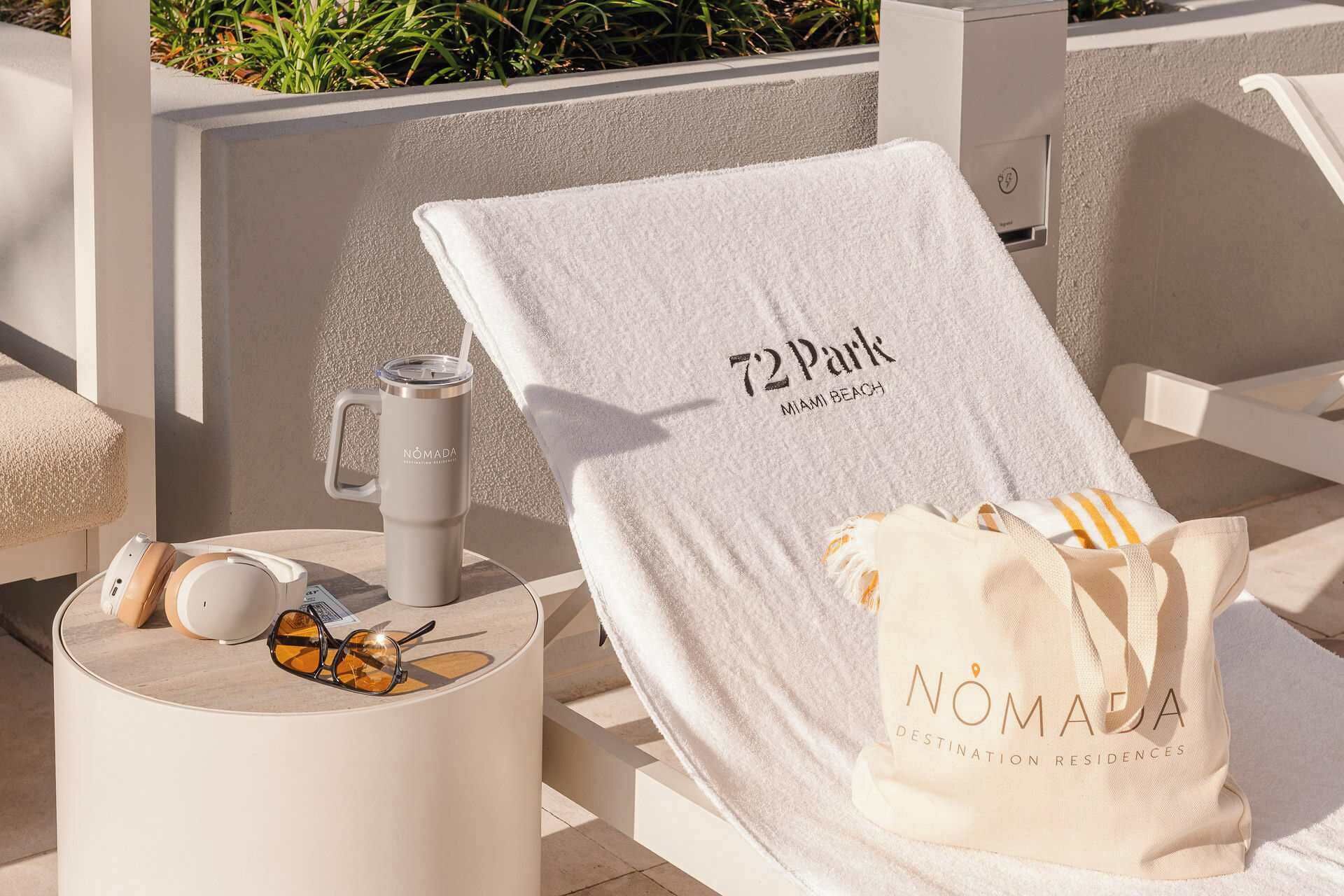 A sun lounger with a towel, a water bottle, and a bag labeled 'NOMADA' on a terrace.