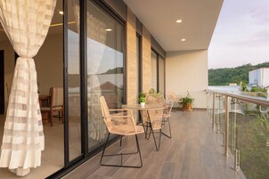 Un balcón con mobiliario de mimbre, una puerta de cristal y vistas a un edificio de hotel.
