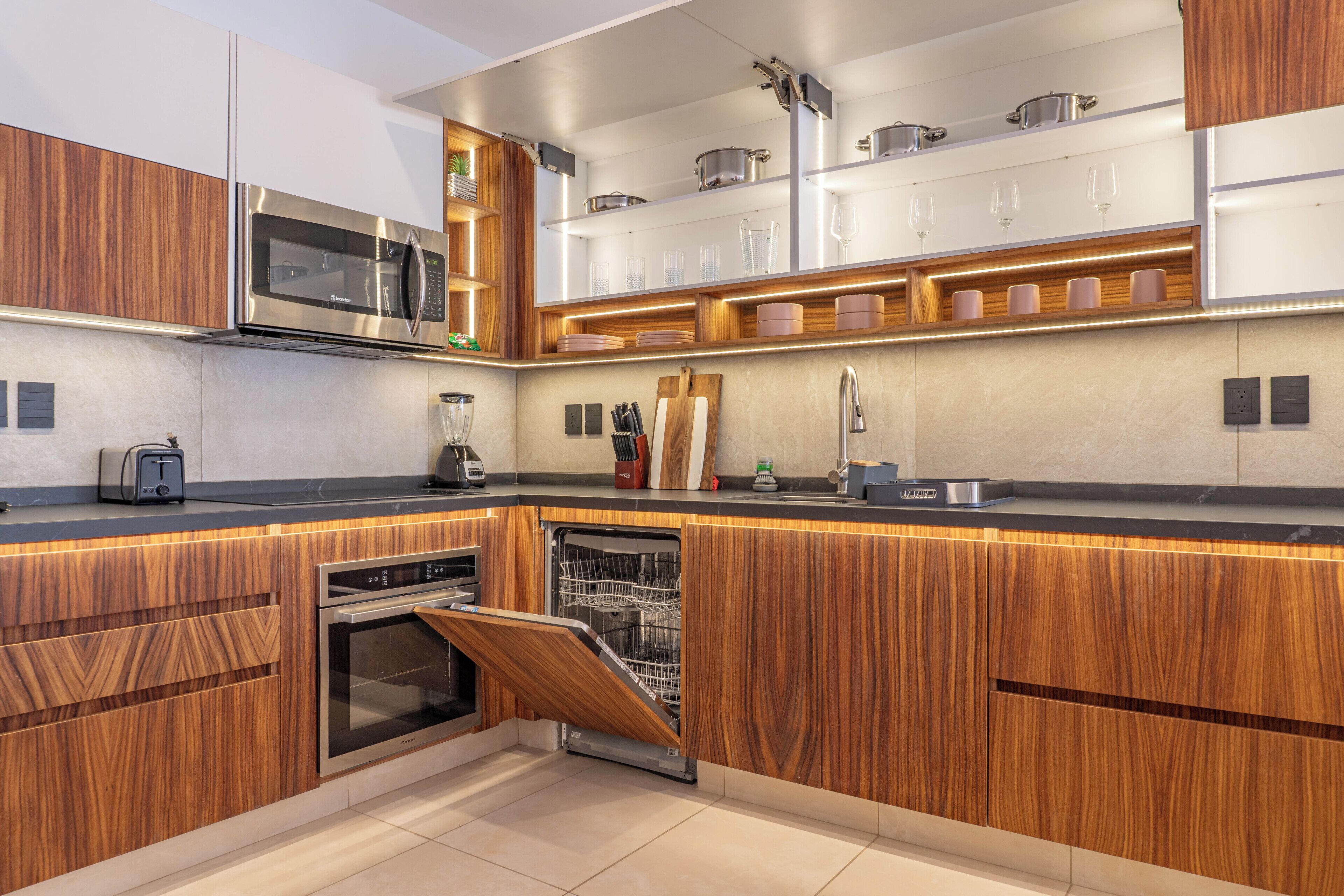 A modern kitchen with wooden cabinetry, stainless steel appliances, and built-in shelves.