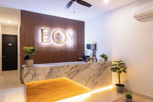 Un mostrador de recepción de hotel con un panel de madera de fondo, una encimera de mármol y un ventilador de techo.