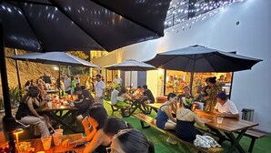 An outdoor dining area with tables and umbrellas, surrounded by a building with string lights. - EOS Suites (Santa Maria Huatulco)