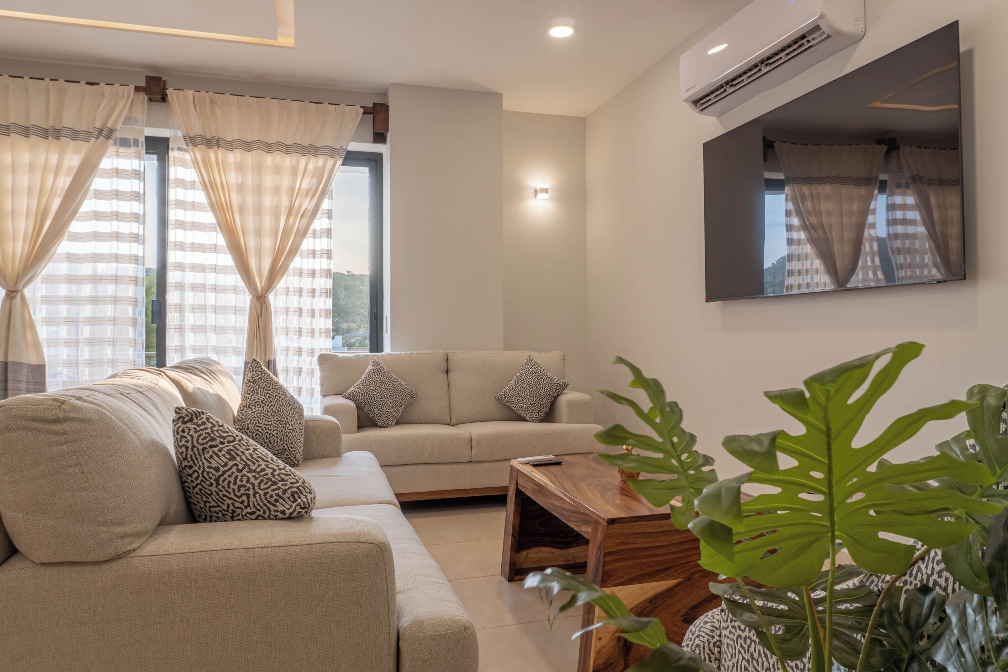 A modern living room with a sofa, a coffee table, and a large mirror.