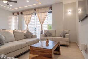 A modern living room with two sofas, a wooden coffee table, and a ceiling fan. - EOS Suites (Santa Maria Huatulco)