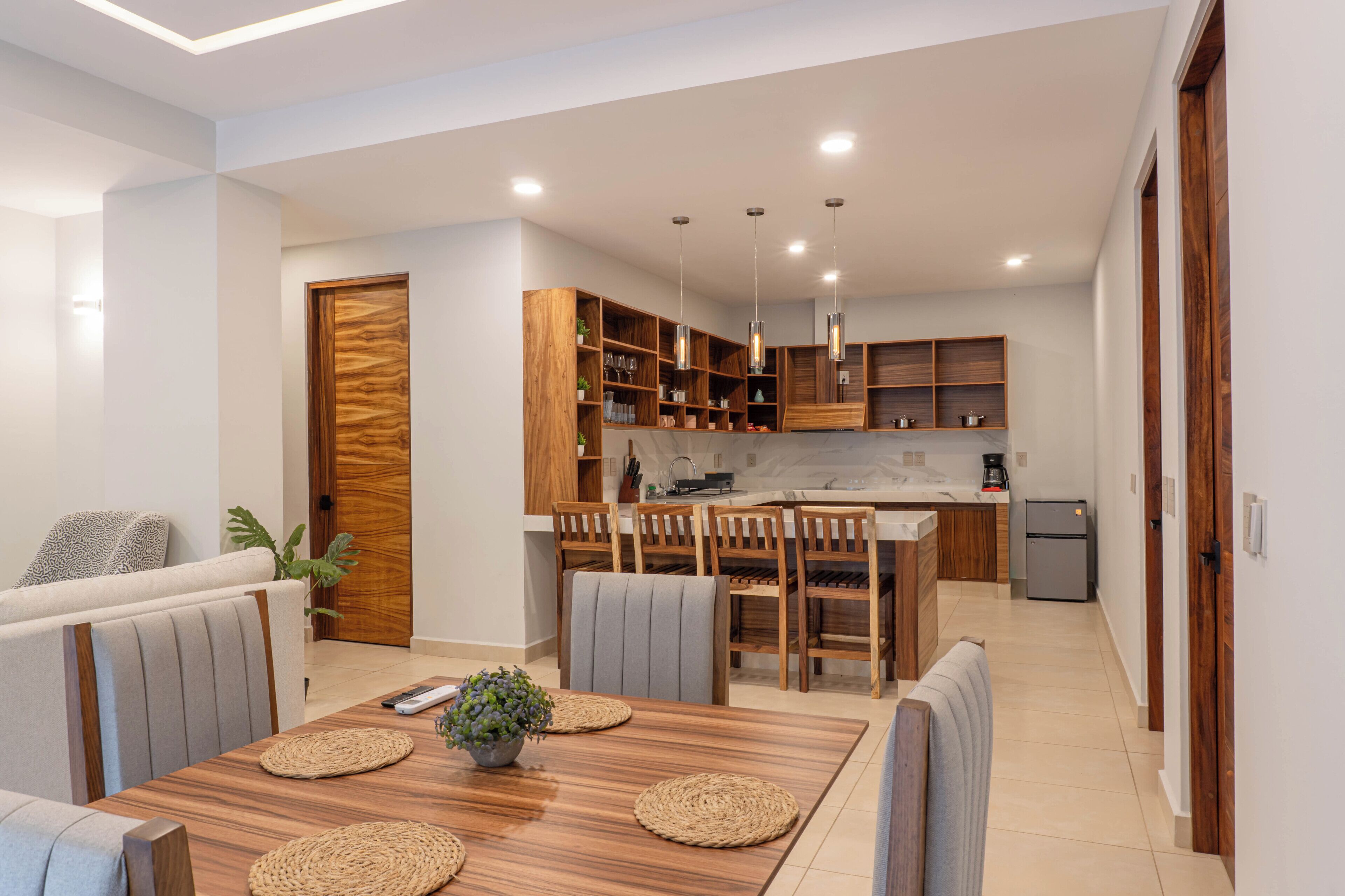 A modern kitchen with wooden cabinets, a central island, and pendant lighting.