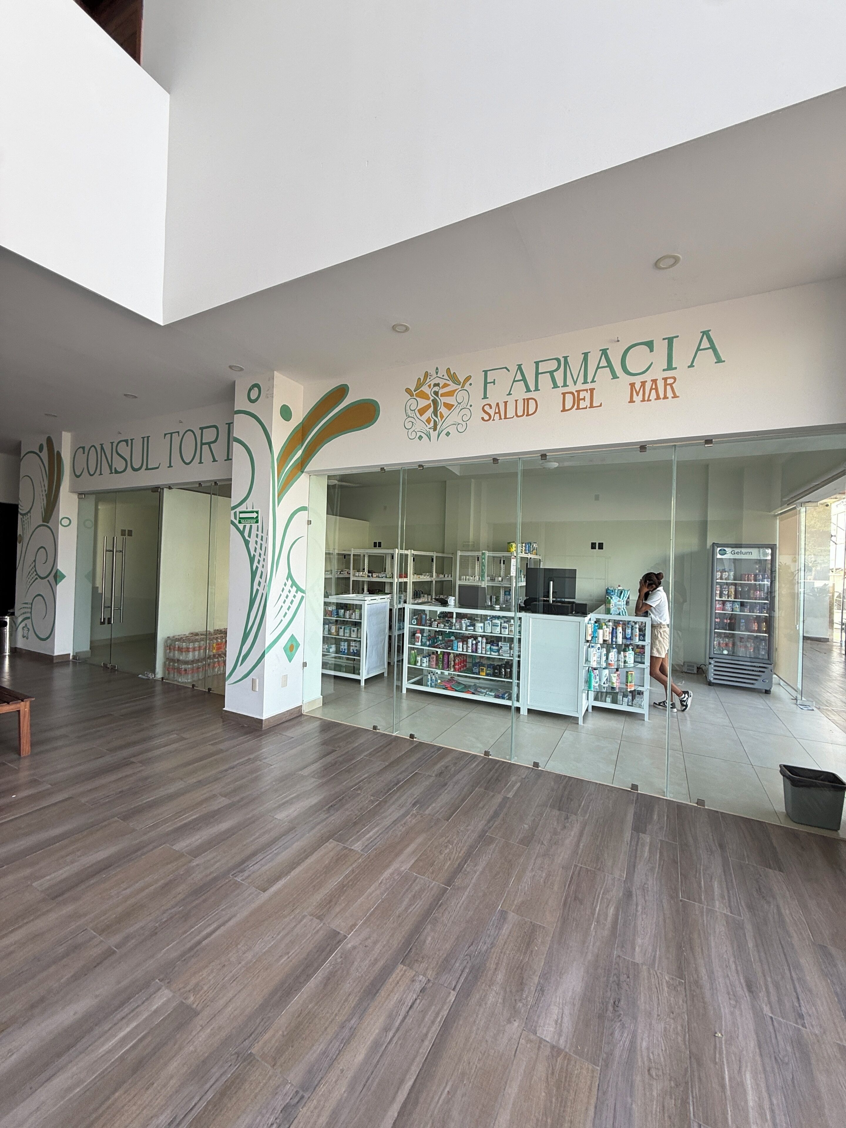 A pharmacy interior with a modern design, including a reception area, shelves stocked with products, and a visible counter.