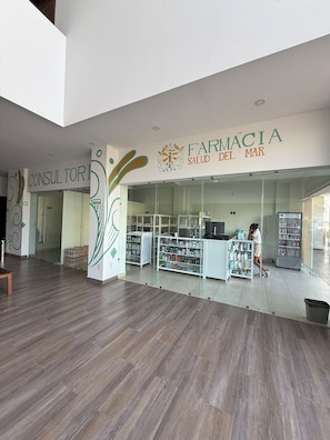 L’intérieur d’une pharmacie présente un design moderne, avec un espace d’accueil, des étagères remplies de produits et un comptoir bien visible.