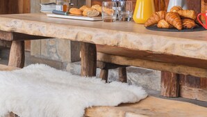 A rustic wooden table with breakfast items including croissants, a glass of orange juice, and a mug.