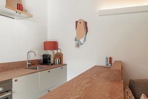 Una cocina moderna con encimera de mármol, electrodomésticos de acero inoxidable y una lámpara roja.