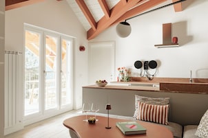 Una cocina moderna con una isla grande, muebles blancos y vistas a la terraza exterior.
