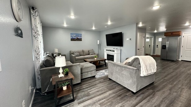 A modern living room with grey sofas, a flat-screen TV, and a fireplace.