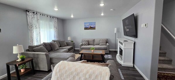A modern living room with a grey sofa set, a coffee table, a TV, and a fireplace.