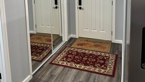 A hallway with a mirrored closet door, a small window, and a red and gold patterned rug.