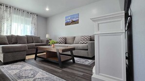 A living room with two grey sofas, a wooden coffee table, and a patterned rug.