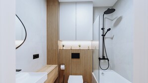Ein modernes Badezimmer mit einem Holzkosmetikschrank, einer Toilette, einer Badewanne und einer Dusche.
