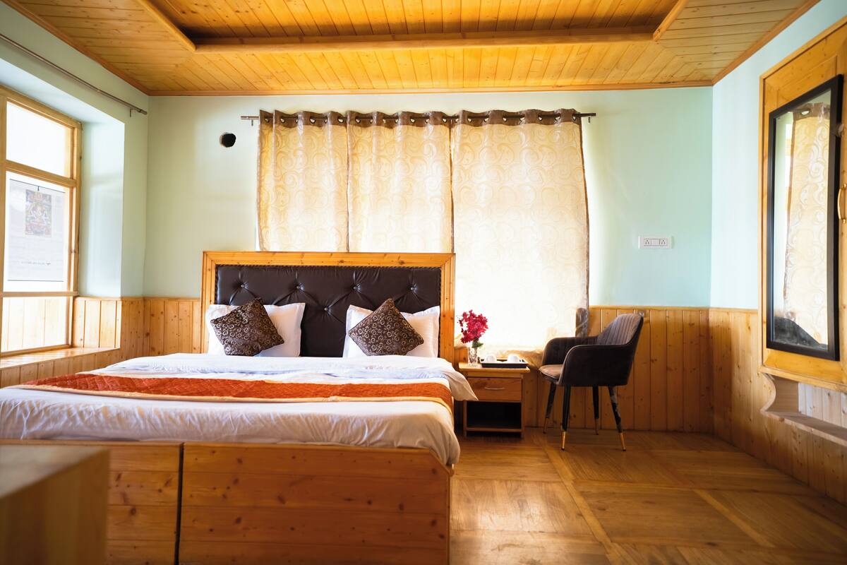 A wooden-paneled bedroom with a large bed, a desk, and a chair.