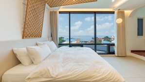 Ein modernes Schlafzimmer mit großem Bett, Meerblick und Balkon.