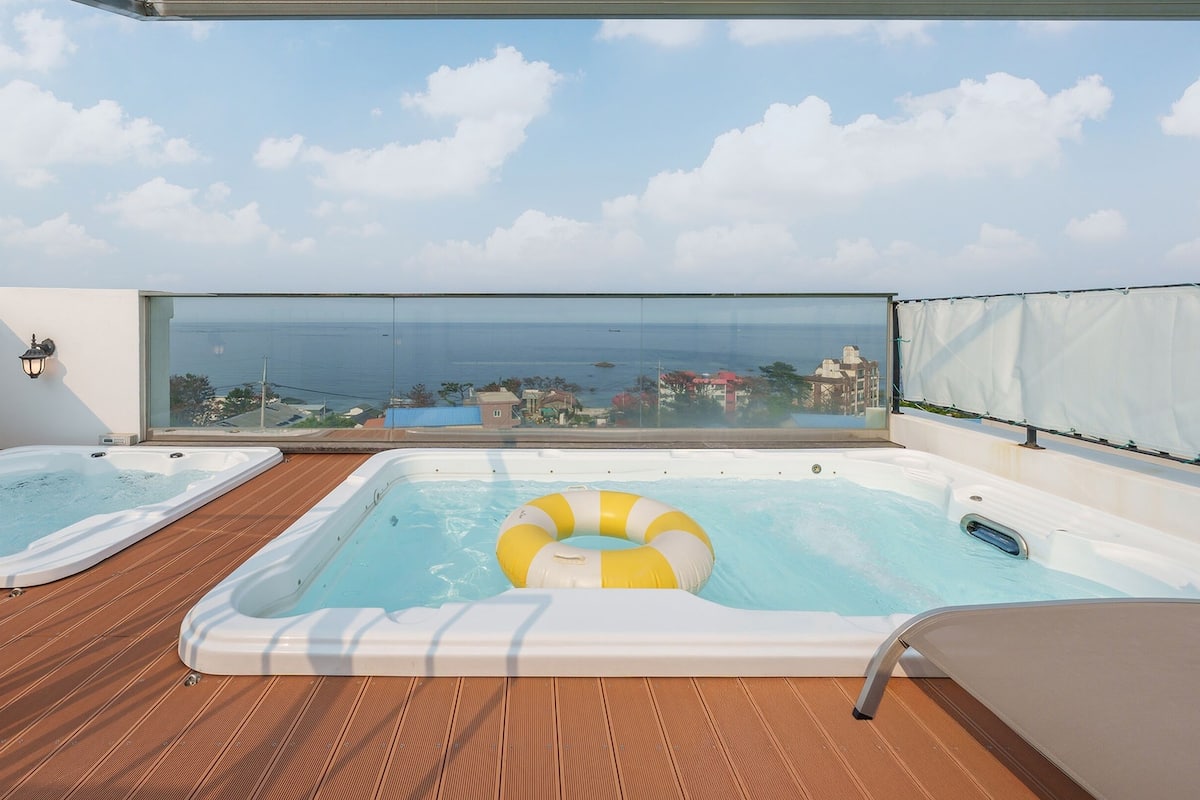 A rooftop terrace with two hot tubs and a view of the sea.